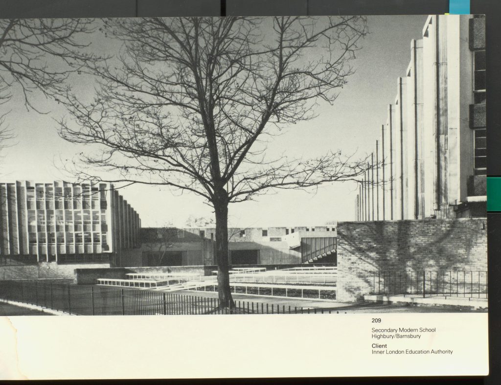 Black and white photograph of building with tree in the foreground.